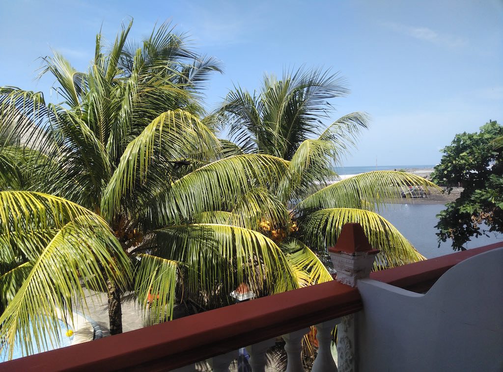 Blick vom Balkon im Sabas Beach Resort. Palmen im Vordergrund, im Hintergrund der pazifische Ozean.